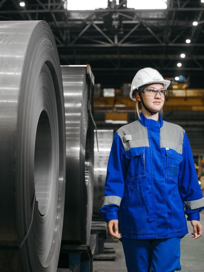 An engineer in blue coveralls, helmet and safety glasses walking through a plant